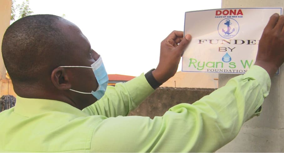 David from DONA adds a temporary sticker to a well, 2021 man putting up a poster