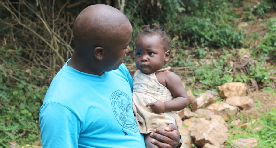 Sam from RWIDF team connects with the local community, 2021 man holding baby