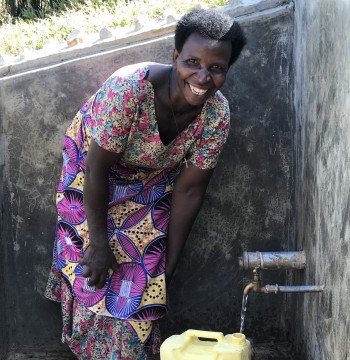 woman filling container from well